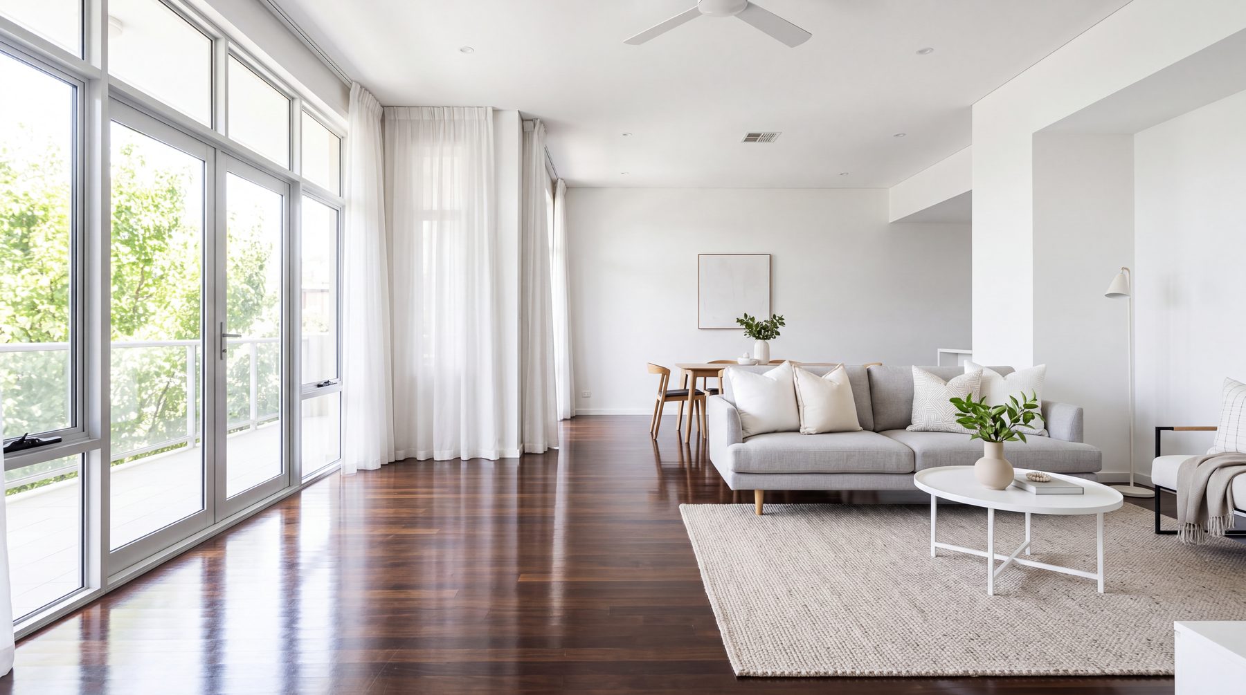 Sunlit empty living room with polished floors, squared cushions and still curtains