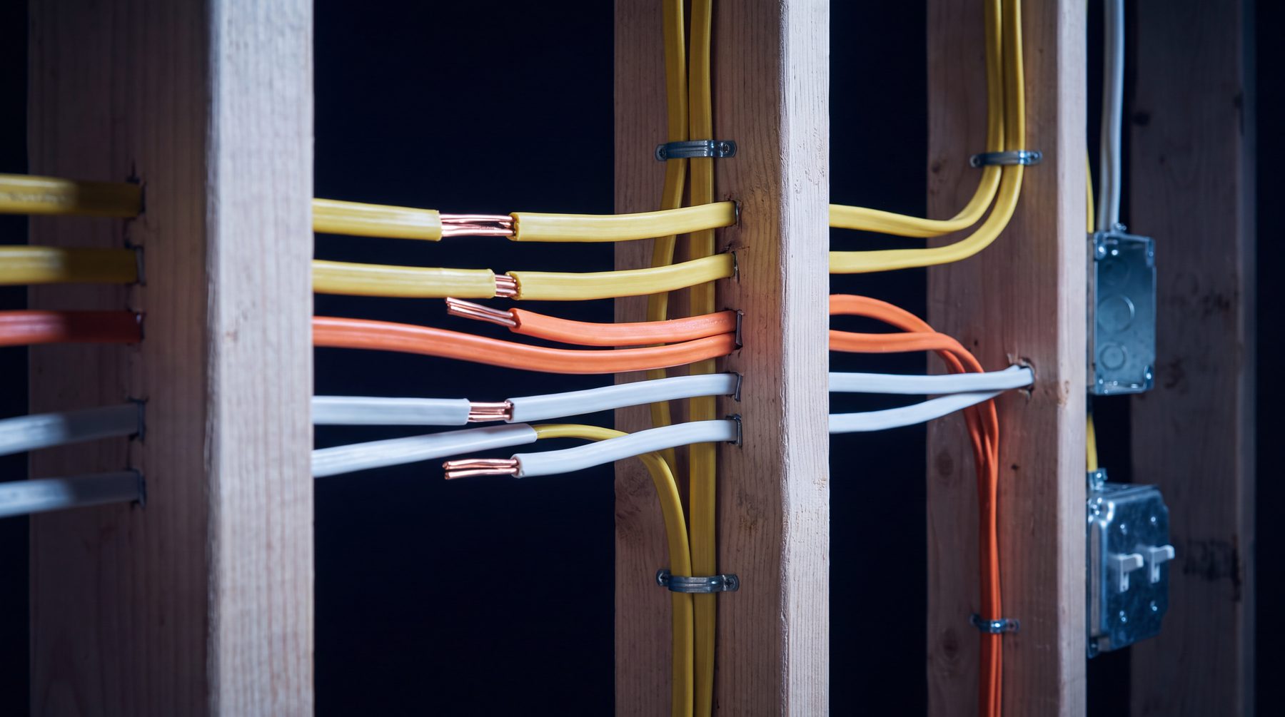 Rough-in wiring in an open stud wall, cables stapled in neat parallel runs