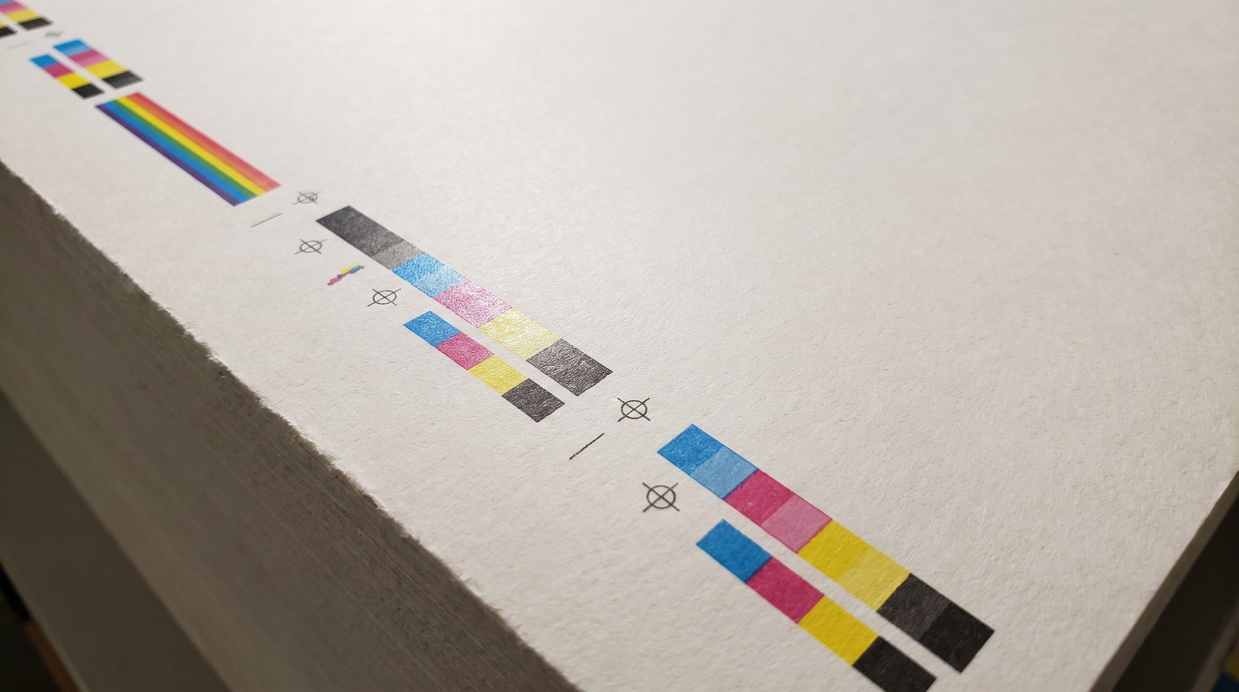 Colour bar and registration marks on the edge of a press sheet under raking light
