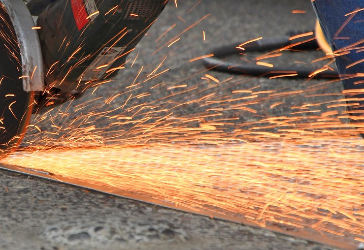 Grinding disc throwing a fan of sparks across a fabrication shop floor